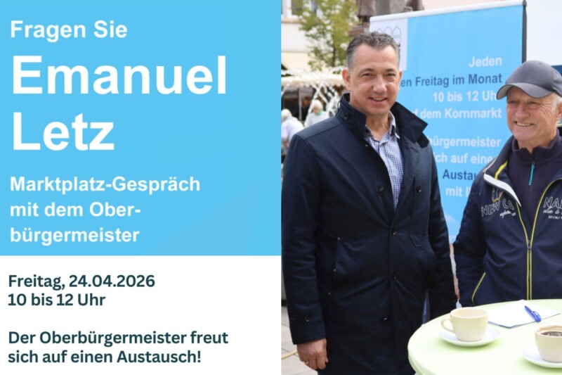 Zwei Männer stehen an einem Tisch mit Kaffeetassen, während sie über ein Marktplatz-Gespräch diskutieren.