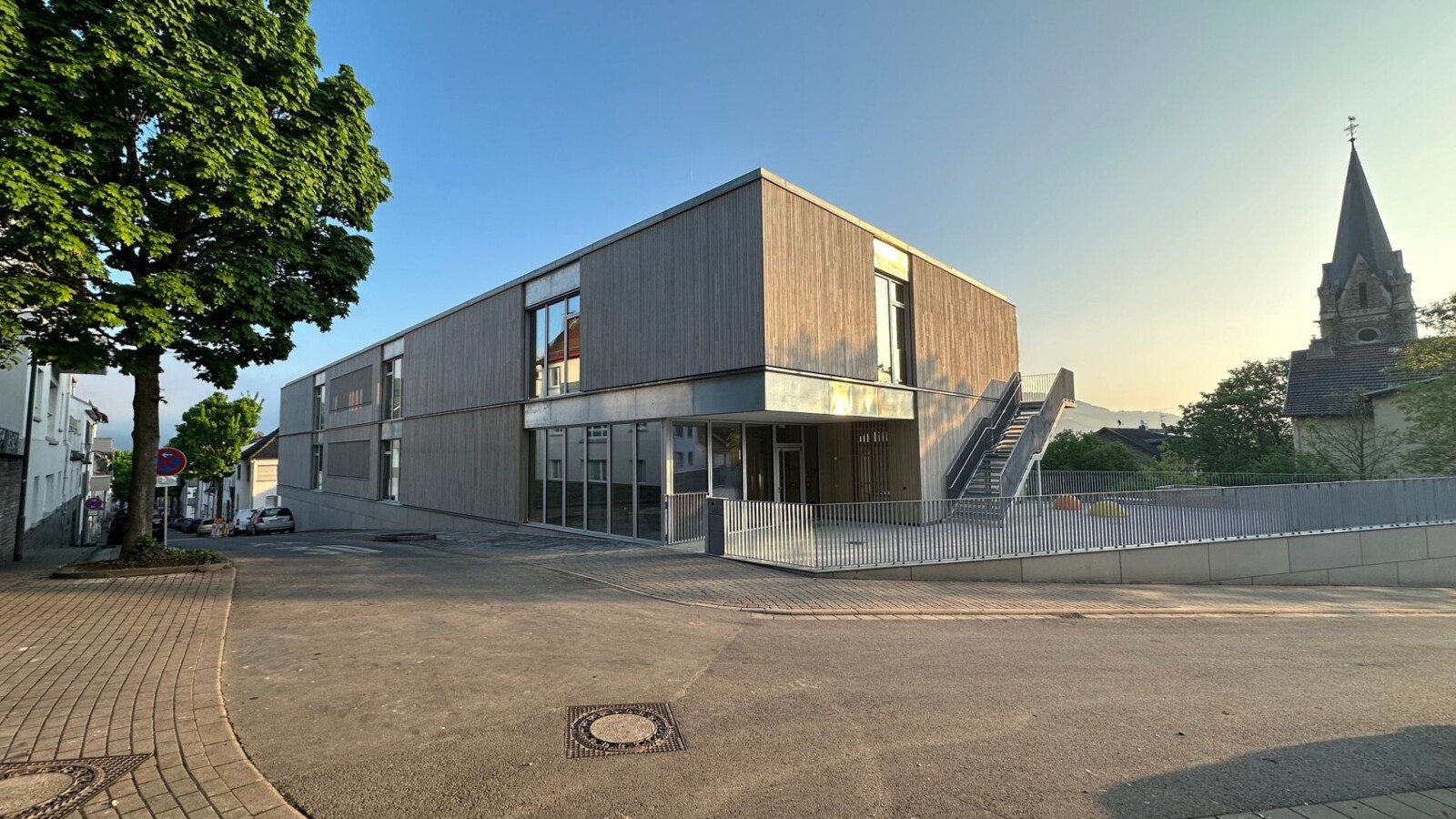 Moderne Architektur eines Holzgebäudes in einer Stadtlandschaft mit Kirche im Hintergrund.