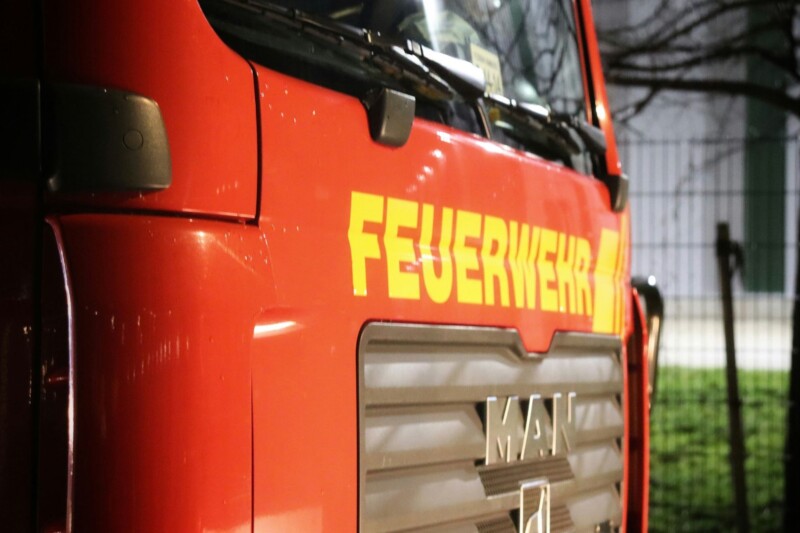 Nahaufnahme eines Feuerwehrfahrzeugs mit dem Schriftzug Feuerwehr in leuchtendem Gelb auf rotem Hintergrund.