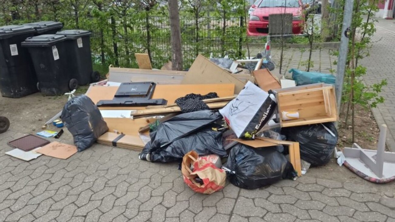 Ein Haufen Müll und Abfall, bestehend aus Möbeln und Plastiktüten, auf einem Gehweg abgeladen.