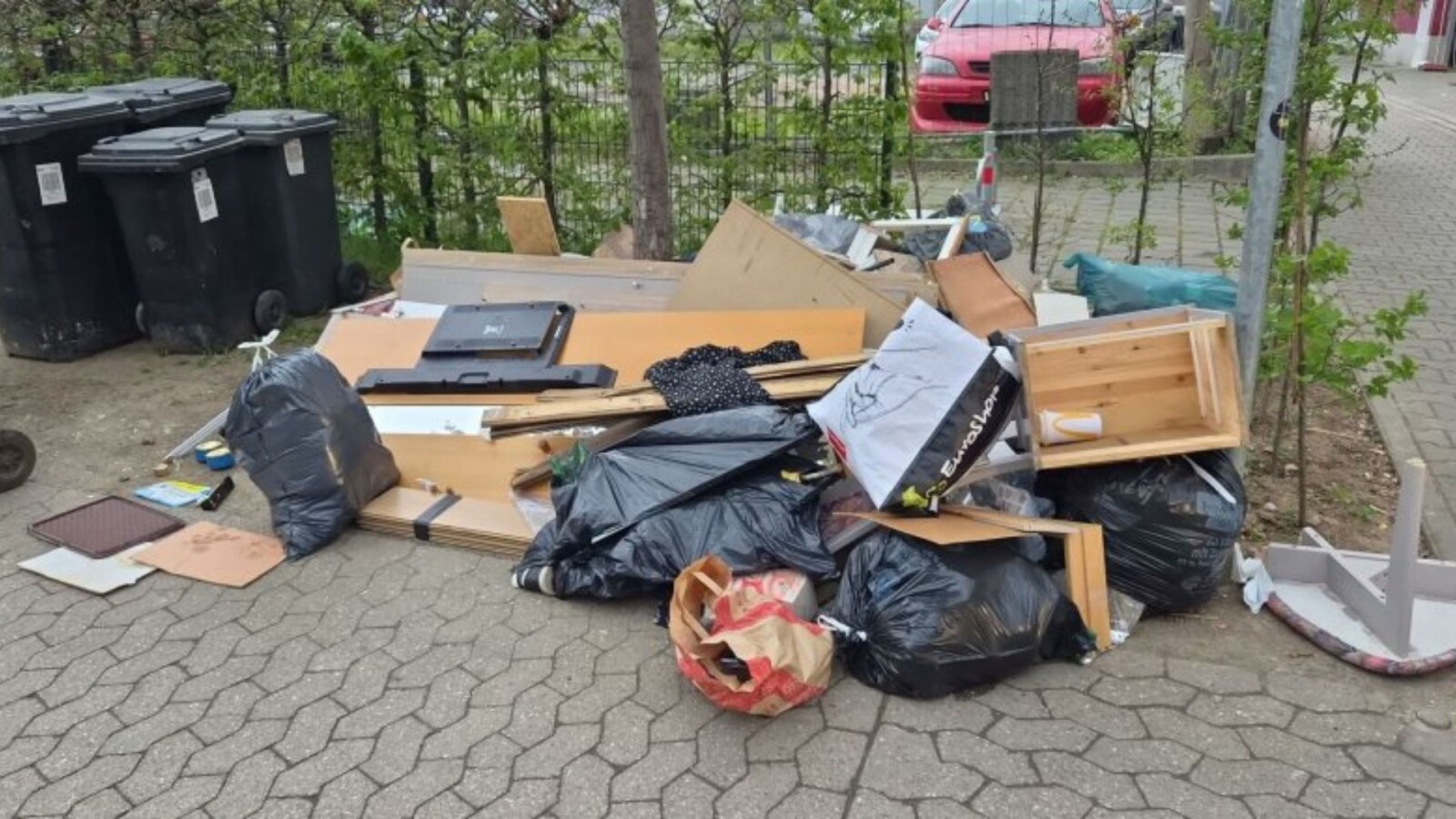 Ein Haufen Müll und Abfall, bestehend aus Möbeln und Plastiktüten, auf einem Gehweg abgeladen.