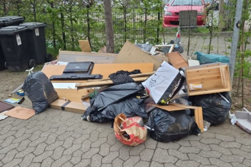 Ein Haufen Müll und Abfall, bestehend aus Möbeln und Plastiktüten, auf einem Gehweg abgeladen.