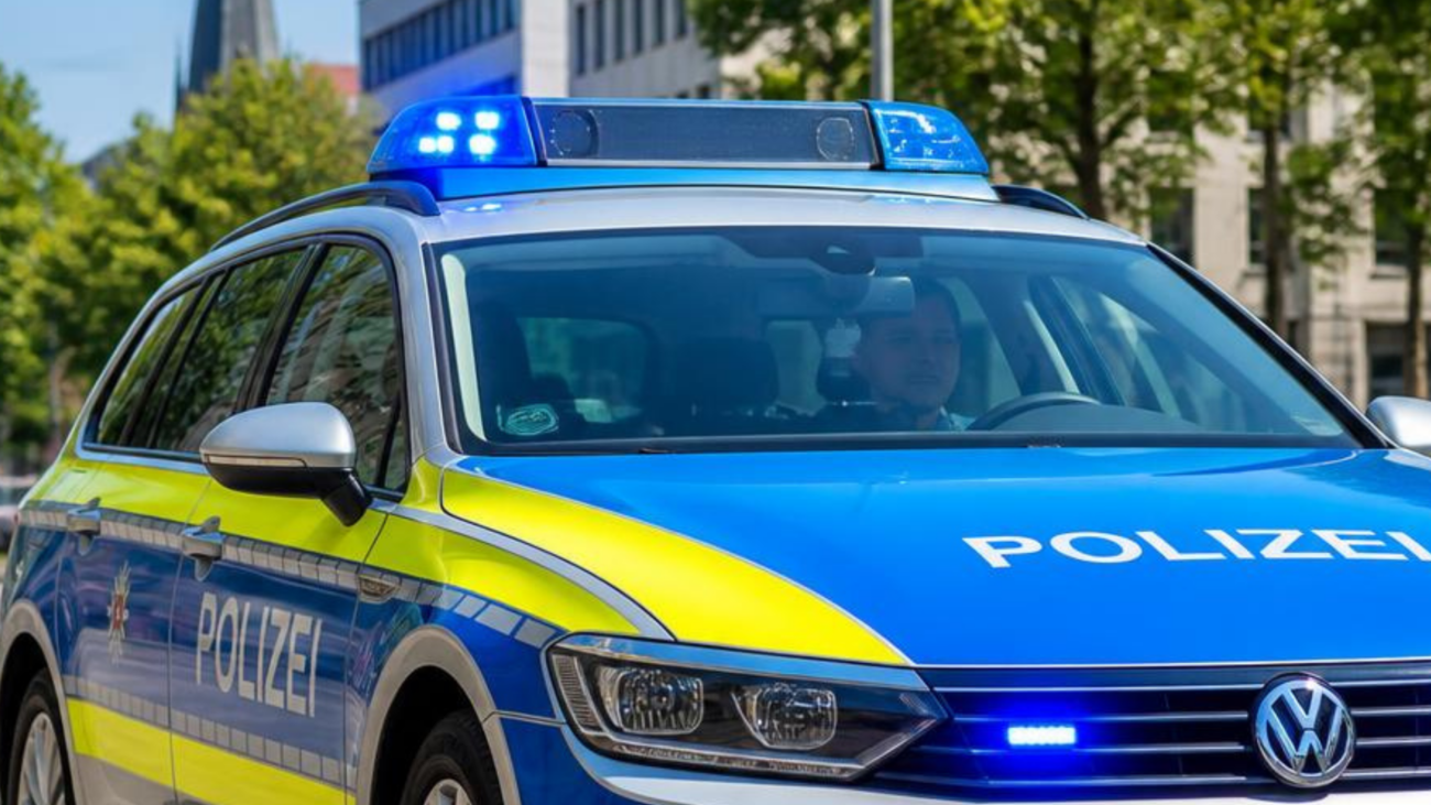 Blaues Polizeiauto mit gelben Streifen an den Seiten. Auf dem Dach ein Blaulicht. Auf der Motorhaube sowie auf der Tür an der Seite ist der Schriftzug Polizei zu lesen.