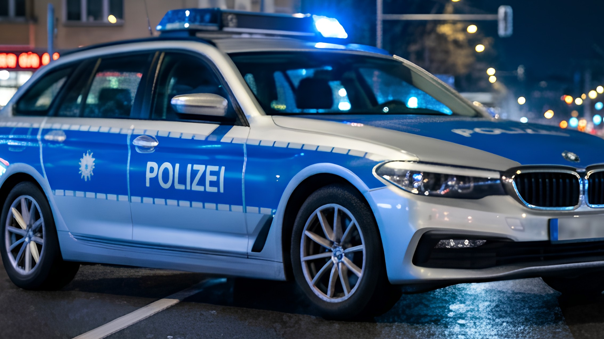 Ein blaues Polizeiauto steht auf einer Straße. Es ist Abend.