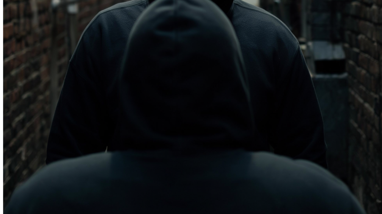 Symbolbild KI-generiert: Mann in Kapuzenpullover bei Nacht