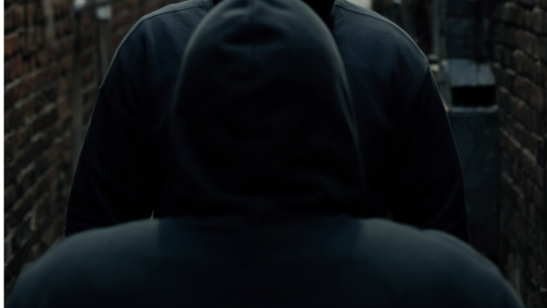 Symbolbild KI-generiert: Mann in Kapuzenpullover bei Nacht